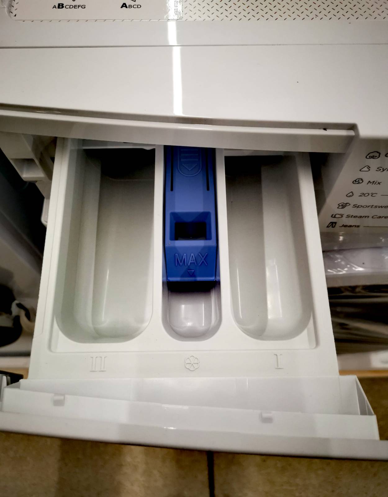 Szuflada pralki - oznaczenia - Przegródka oznaczona symbolem kwiatka; Przegródka z symbolem kropli; Przegródka z symbolem pojemnika